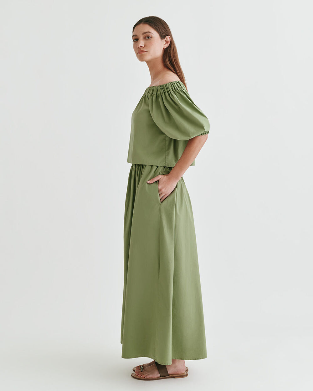 Poplin Off-The-Shoulder Cropped Top Woman standing in a studio with hands on hips, wearing a long dress and sandals.