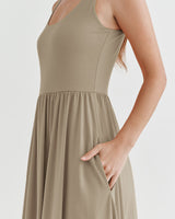 Woman in a sleeveless dress, partial view, hand on hip.