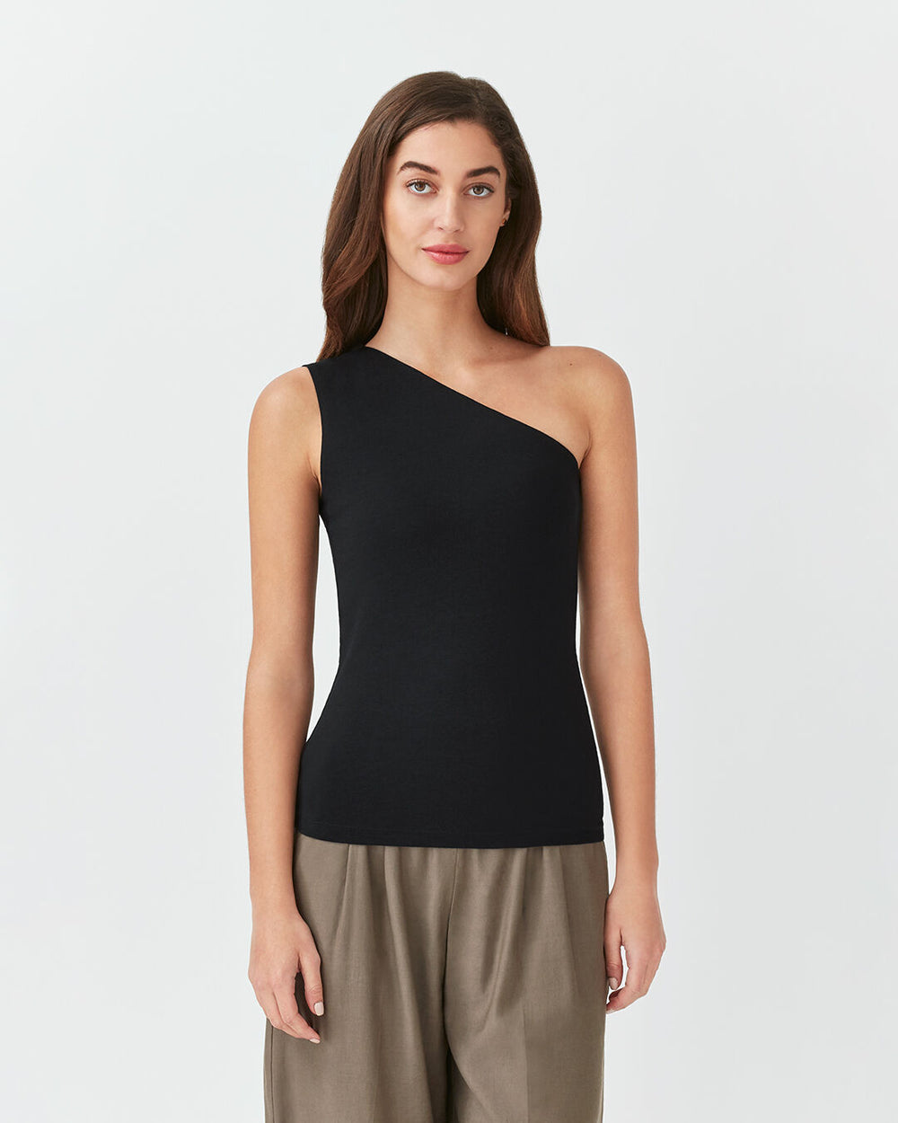 Woman in a one-shoulder top and pants standing straight.