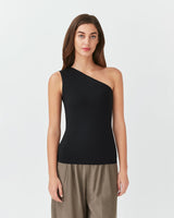 Woman in a one-shoulder top and pants standing straight.