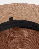 Close-up of a woven hat with a band around it.