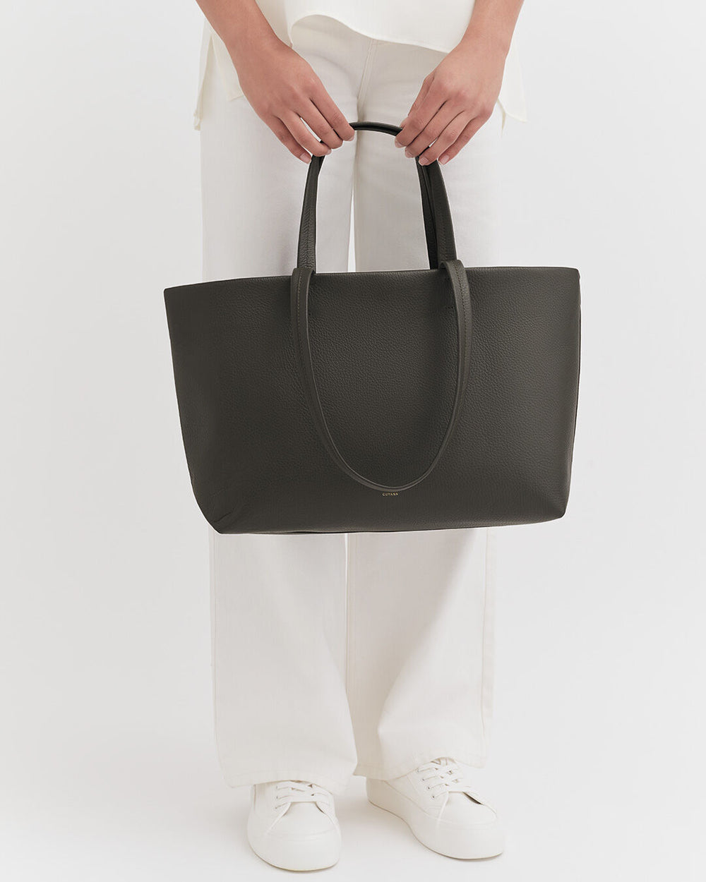 Person holding a large tote bag while standing.