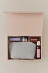 Open box containing a toiletry bag and assorted skincare products.