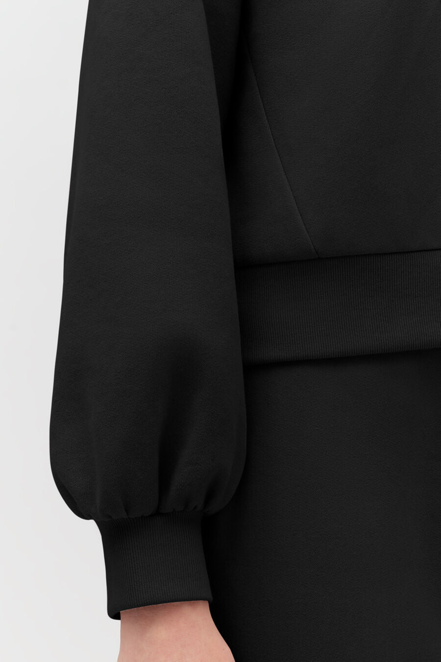 Close-up of a person wearing a long-sleeved garment with cuffs.