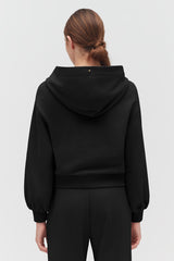 Person seen from behind wearing a hooded top and pants.