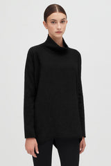 Woman standing in turtleneck top and pants