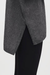 Person wearing a draped top and fitted pants.