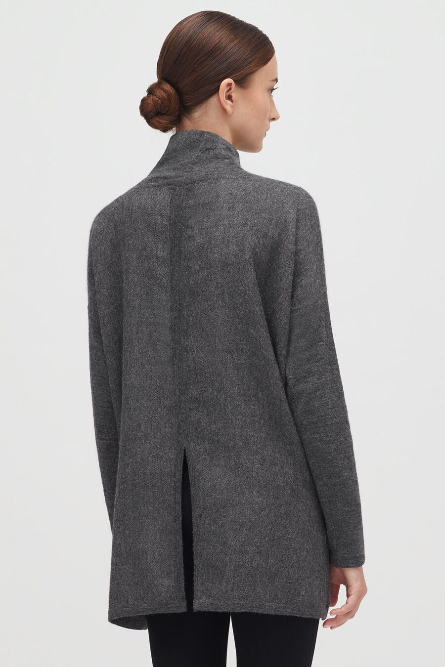 Alpaca Open-Back Turtleneck Sweater Woman in a jacket viewed from back, with a bun hairstyle.