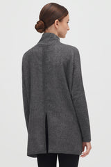 Woman in a jacket viewed from back, with a bun hairstyle.
