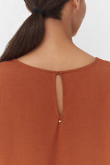 A woman from behind showing the top of her shirt with a button closure.