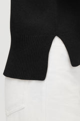 Close-up of a split hem on a sweater laid over another garment.