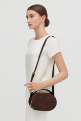 Woman standing side view with a shoulder bag.