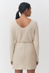 Woman in a sweater and skirt viewed from behind.