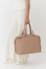 Woman holding a handbag standing in a neutral posture.