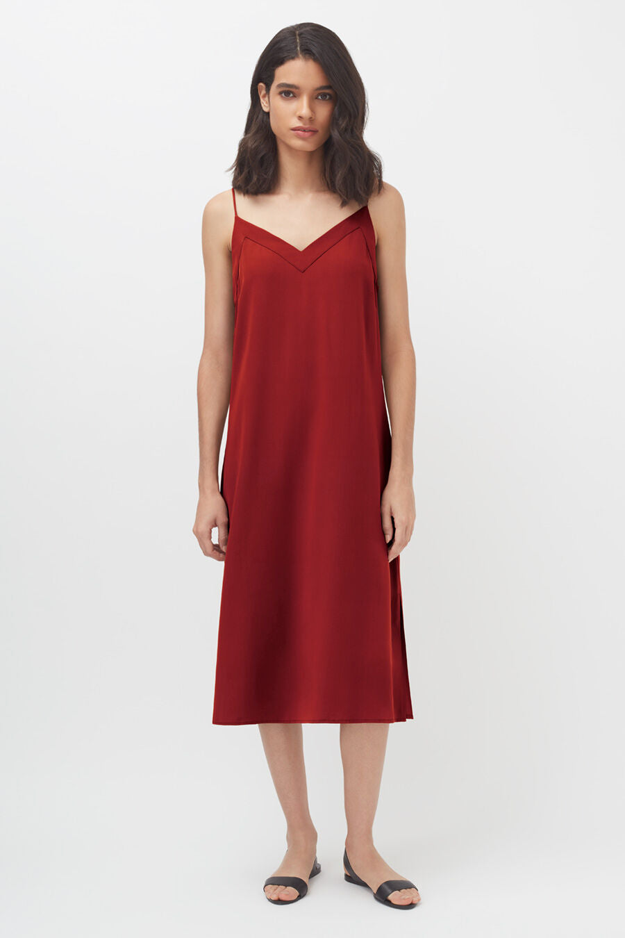 Woman standing in a sleeveless knee-length dress and sandals.