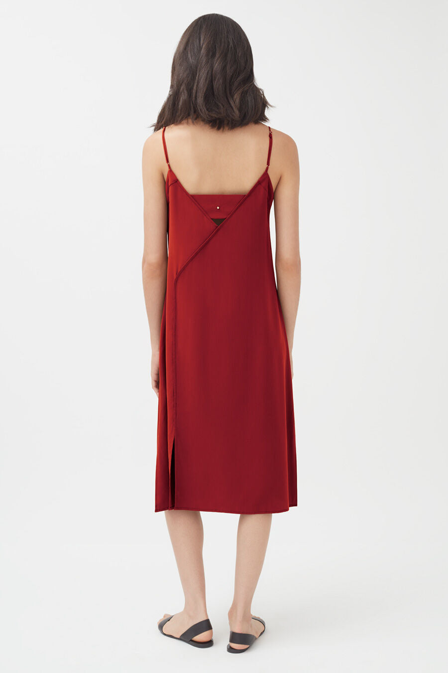 Woman in a sleeveless dress viewed from the back, standing.