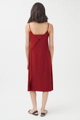 Woman in a sleeveless dress viewed from the back, standing.