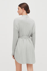 Woman wearing a dress with a tied belt, viewed from the back.