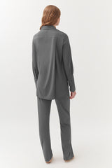 Person standing with back facing the camera, wearing a suit.