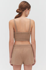 Woman in crop top and shorts seen from the back.