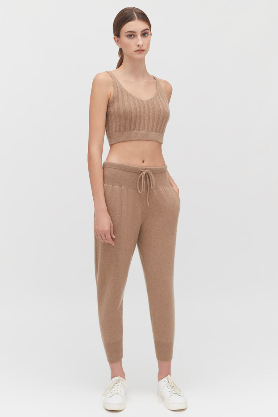 Woman in a two-piece outfit with sneakers standing against a plain background.