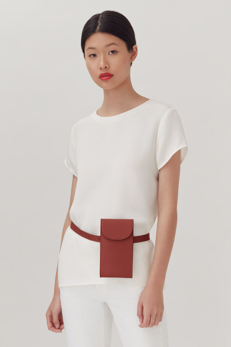 Convertible Belt Bag Woman standing with a belt and pouch, looking at the camera.