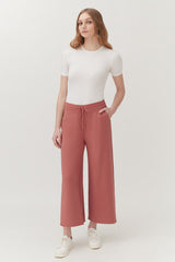 Woman in a short-sleeved top and wide-legged pants standing in a neutral pose.