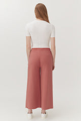 Woman viewed from behind wearing a fitted top and wide-leg pants, standing.