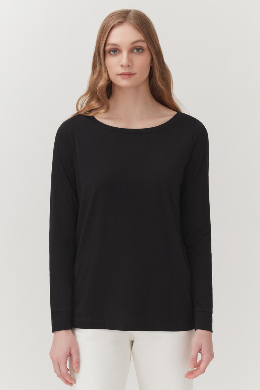 Woman standing in a long-sleeved top and pants, facing forward.