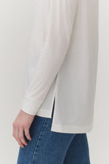 Person in a long-sleeve top and jeans, partial view.