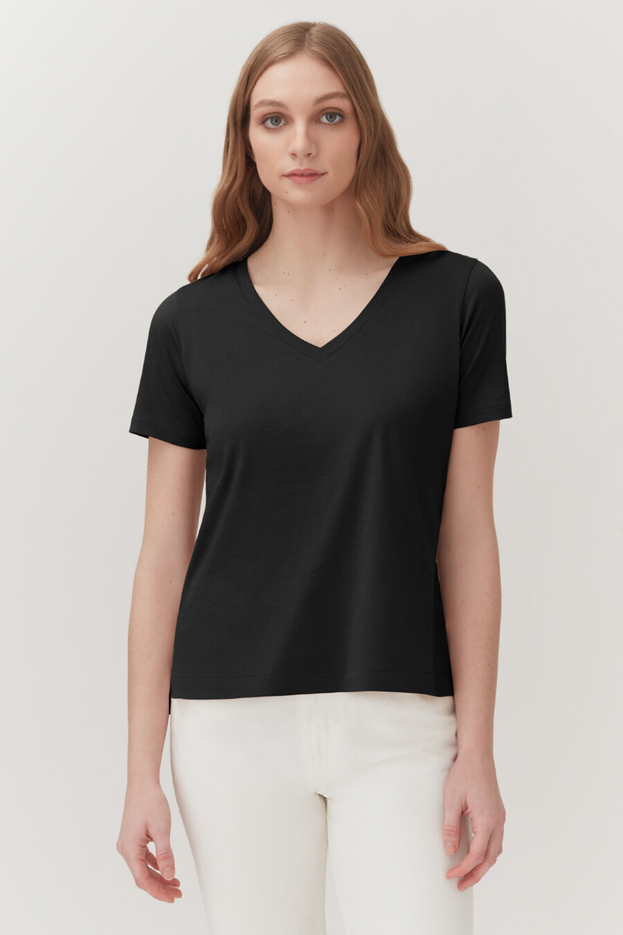 Woman in V-neck T-shirt standing against a plain background.