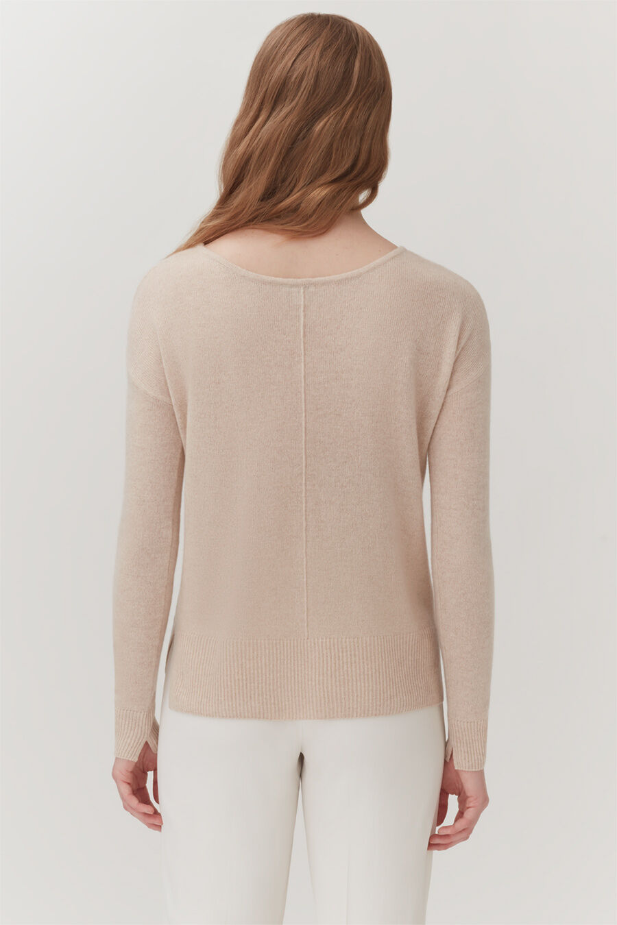 Woman pictured from behind, wearing a sweater and pants.