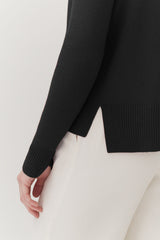 Close-up of a person's side wearing a sweater and touching fabric.