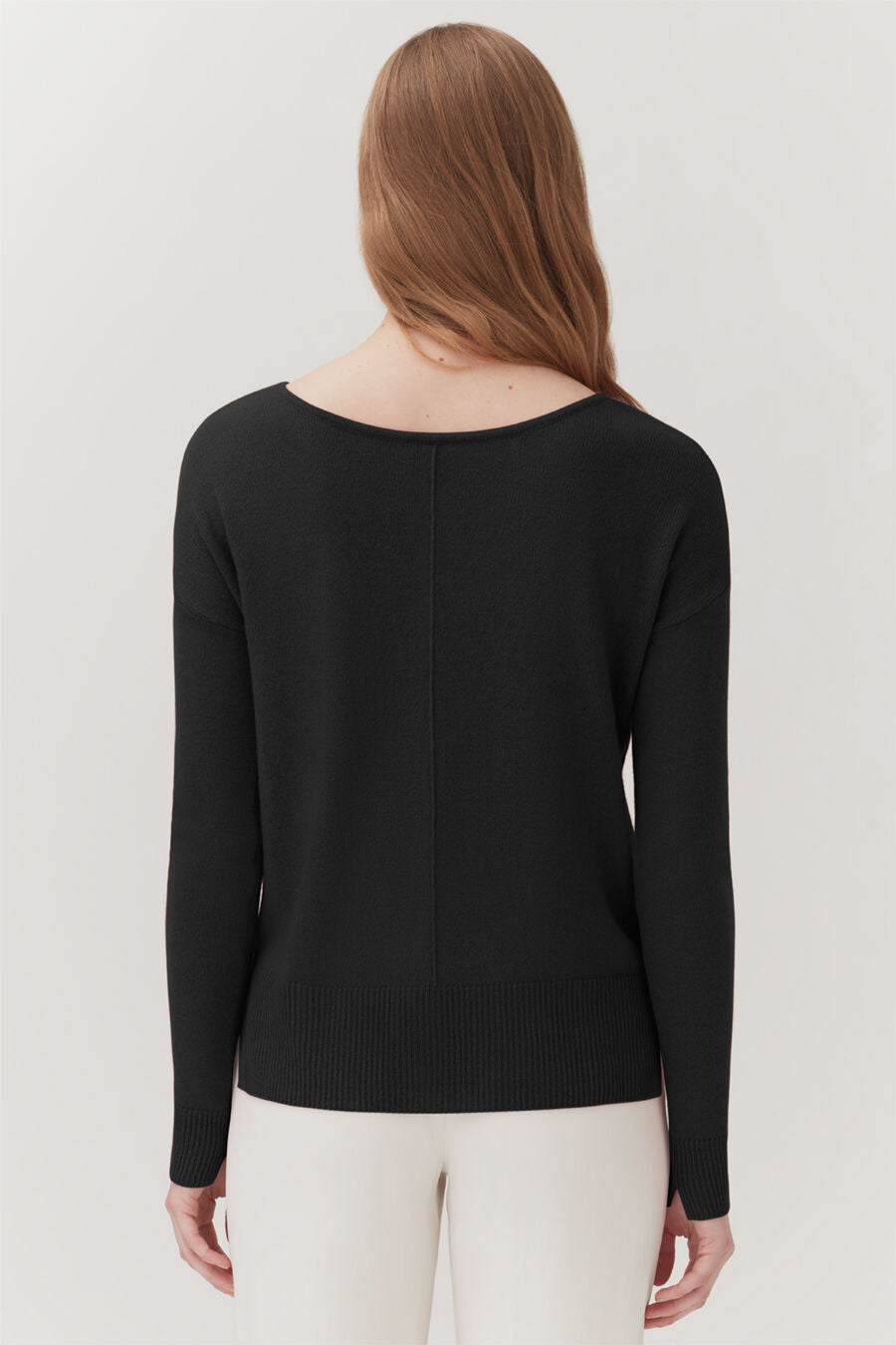 Woman from behind wearing a long-sleeved top and pants.