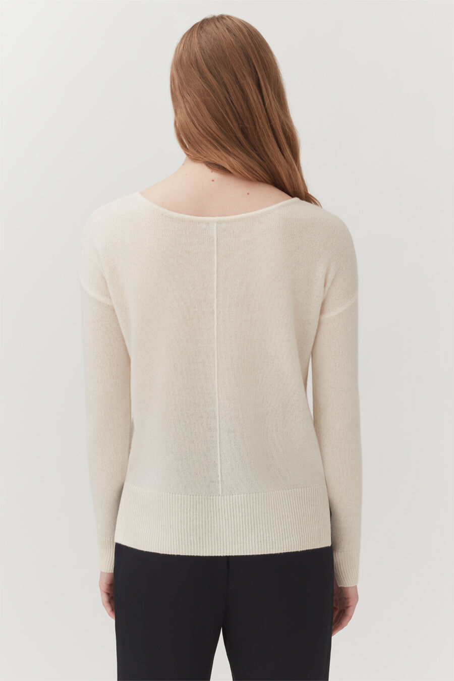 Single-Origin Cashmere Cardigan Rear view of a woman wearing a sweater and pants, standing.