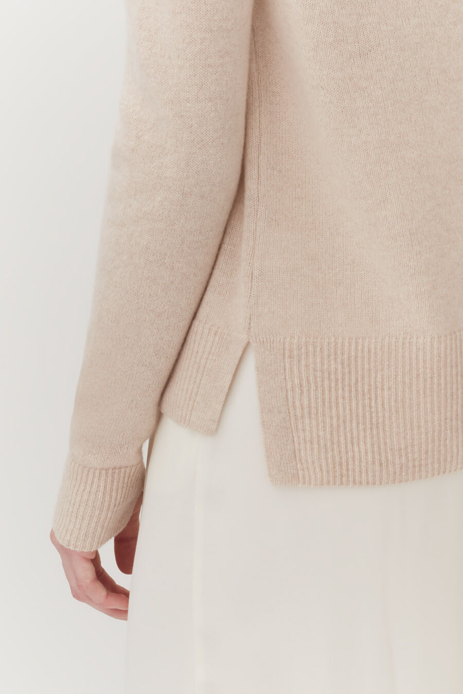 Close-up of a person wearing a sweater and skirt.