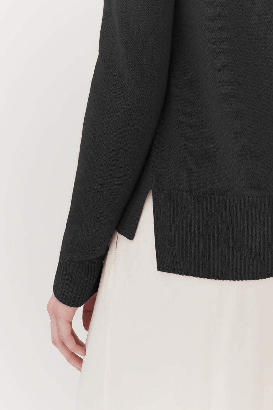 Close-up of a person wearing a sweater and skirt.