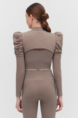 Woman viewed from behind showing back detail of her long-sleeve outfit with open back design.