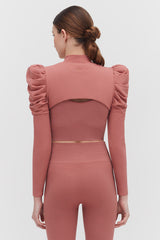 Woman seen from behind wearing a long-sleeve top with puffed shoulders.