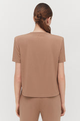 Woman from behind with hair in a bun wearing a short-sleeved top.