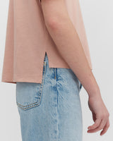 Close-up of a person wearing a t-shirt tucked into denim jeans.