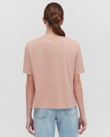 Woman facing away, wearing a T-shirt and jeans, hair in a ponytail.