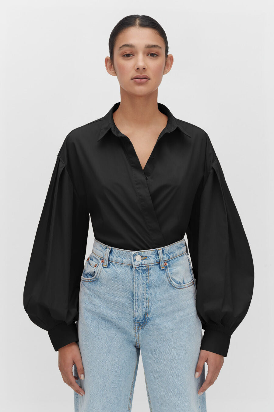Poplin Balloon Sleeve Shirt Woman with hands on hips wearing a blouse and jeans, standing against a plain background.
