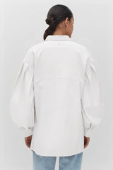 Person facing away from camera wearing an oversized shirt and jeans.