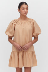 Woman posing in a short dress with puffy sleeves and gathered neckline.