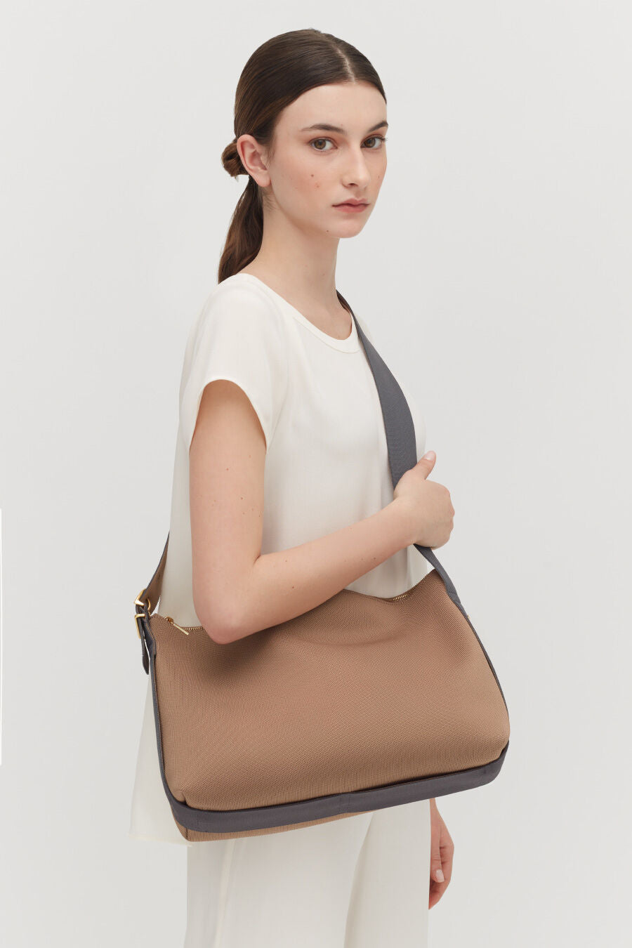 Woman standing with a large shoulder bag.