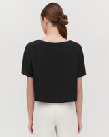 Woman from behind wearing a short-sleeved top and styled hair.