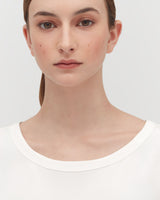 Close-up of a woman facing the camera with a neutral expression.