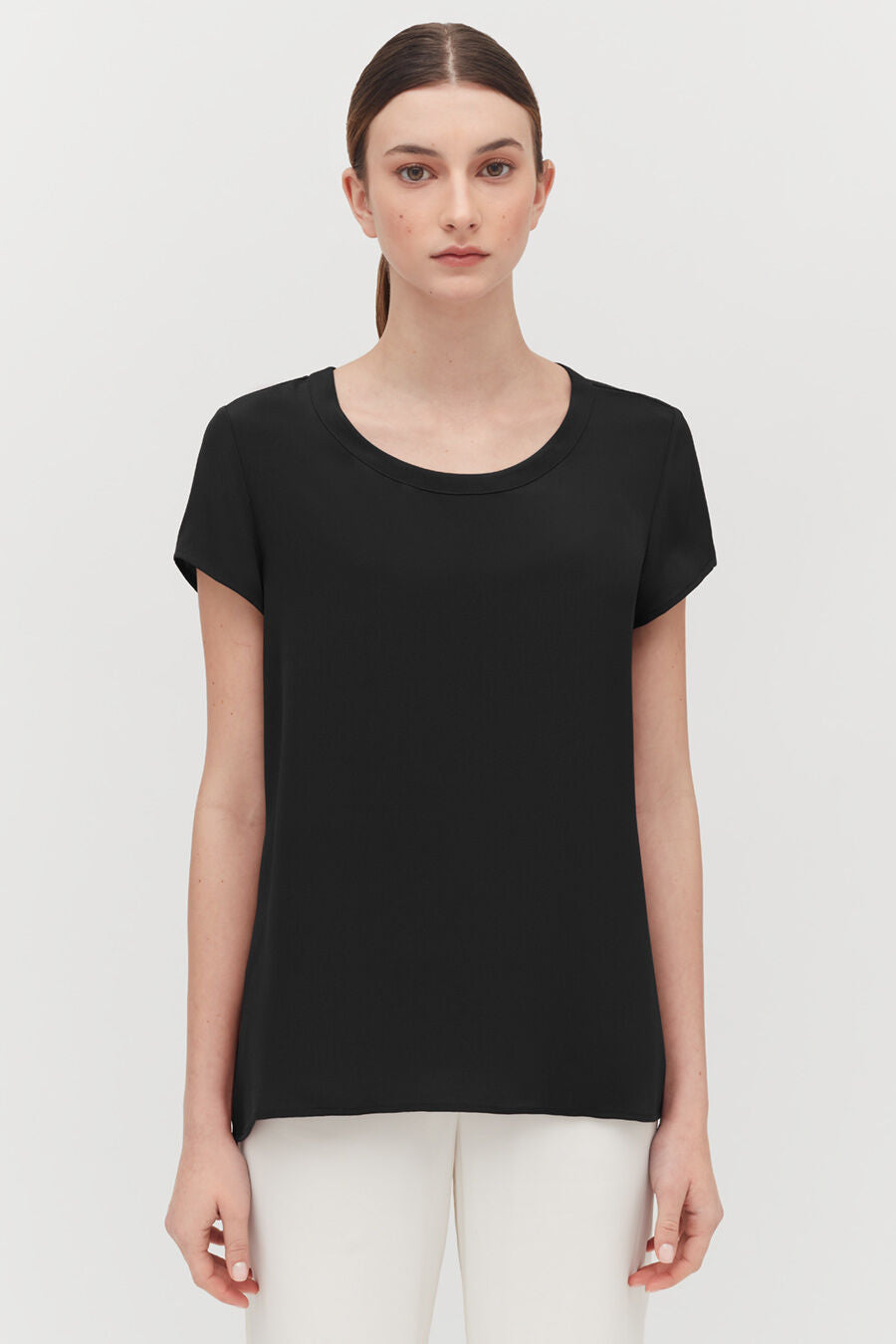Silk High-Low Tee Woman in a short-sleeved top standing with a neutral expression