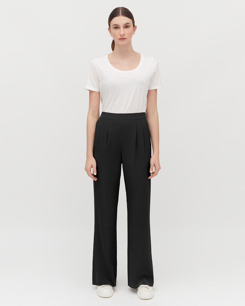 Woman standing in a T-shirt and trousers, facing forward.